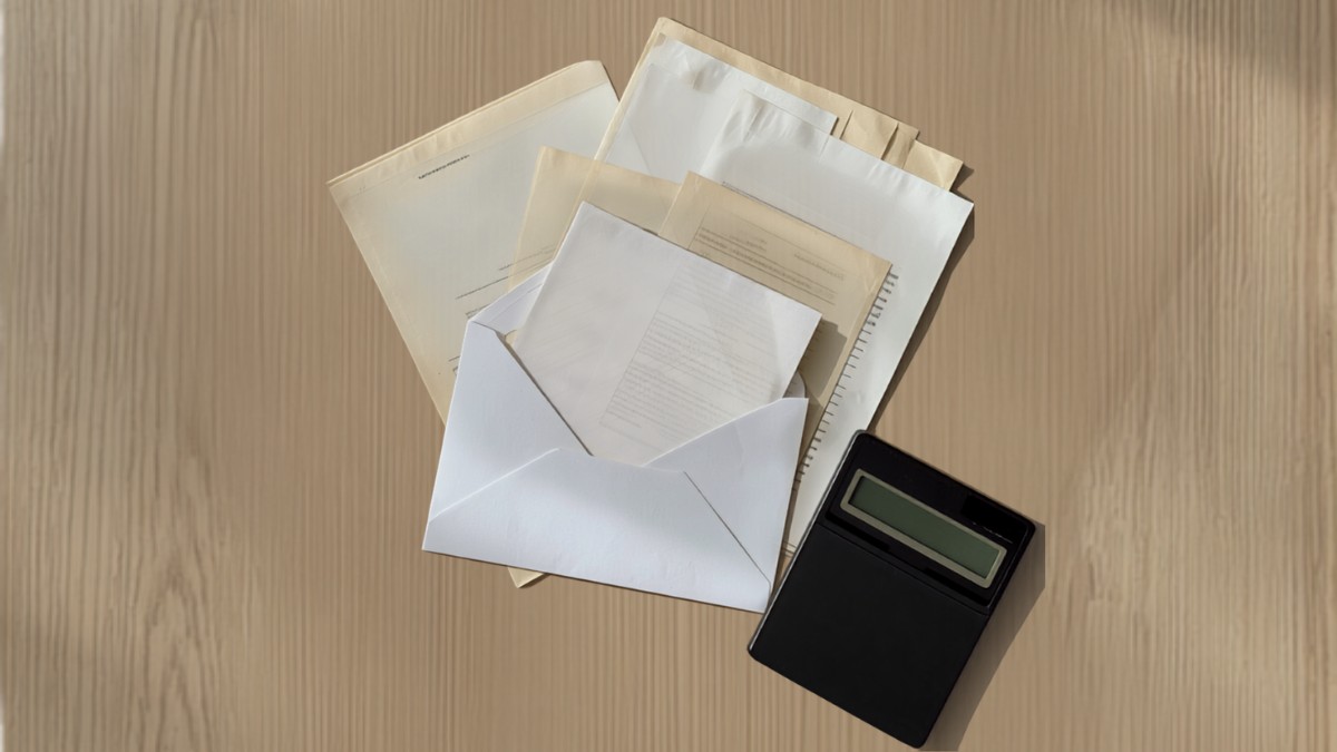 Contas, envelope e calculadora sobre a mesa representando reorganização de dívidas