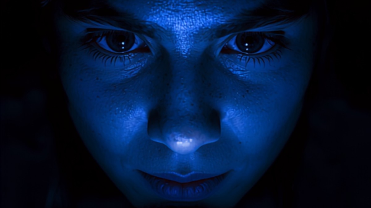 Rosto iluminado pela luz azul de uma tela de celular no escuro
